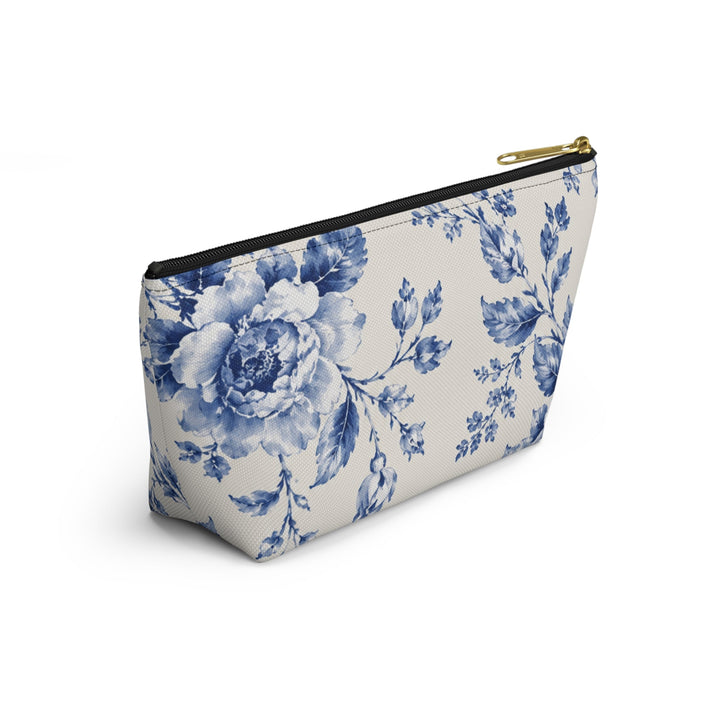 Sunday Theory blue floral toile accessory pouch with a gold zipper pull on a cream canvas background.