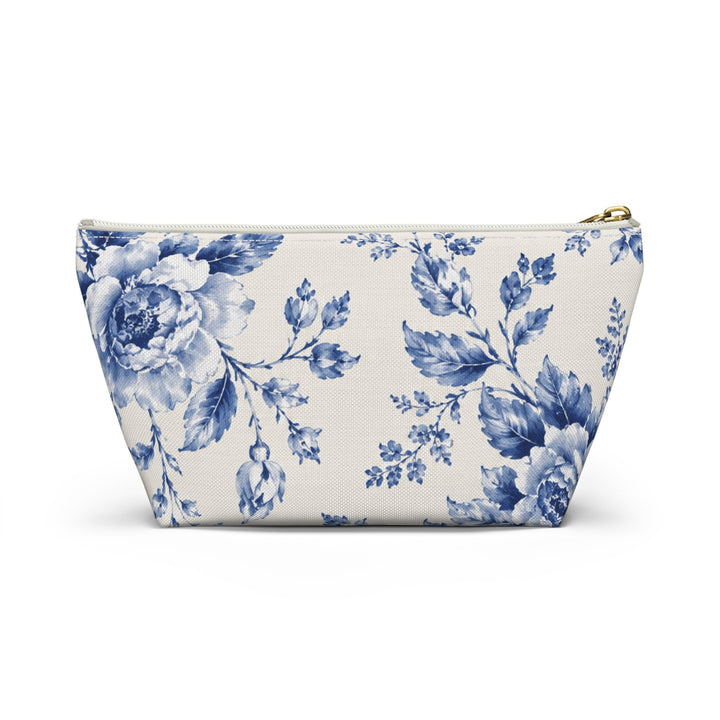 Sunday Theory blue floral toile accessory pouch with a cream canvas base and a gold zipper pull.