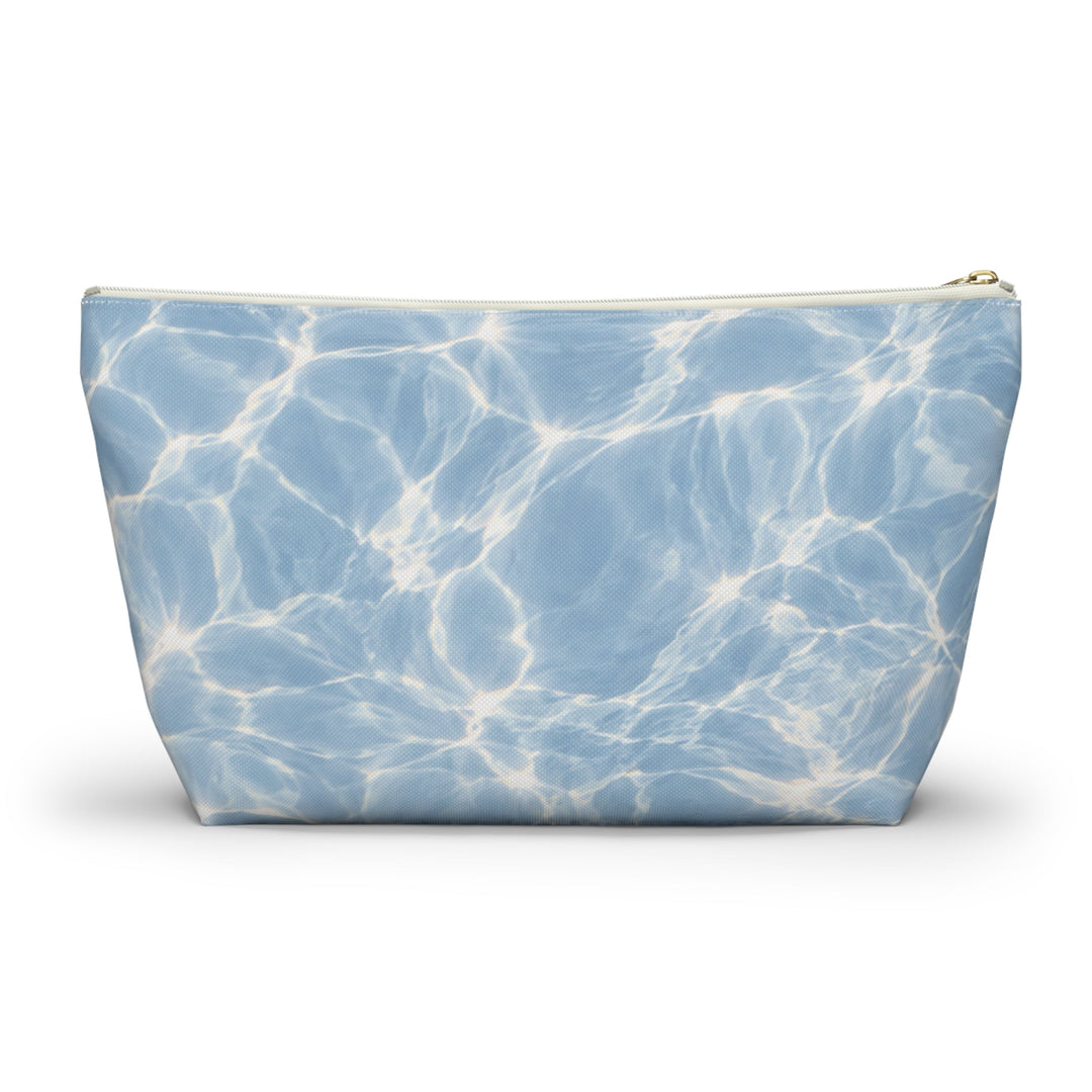 Sunday Theory blue T-bottom accessory pouch with a rippling water print and gold zipper on a white background.