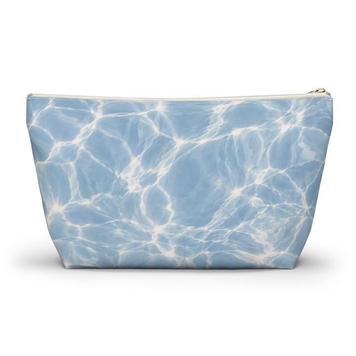 Sunday Theory blue T-bottom accessory pouch with a rippling water print and gold zipper on a white background.