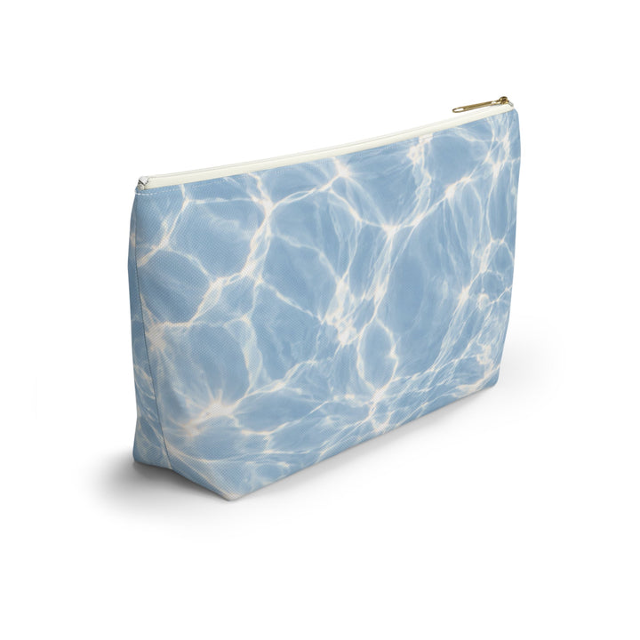 Sunday Theory blue T-bottom accessory pouch featuring a rippling water print and a gold-colored zipper.