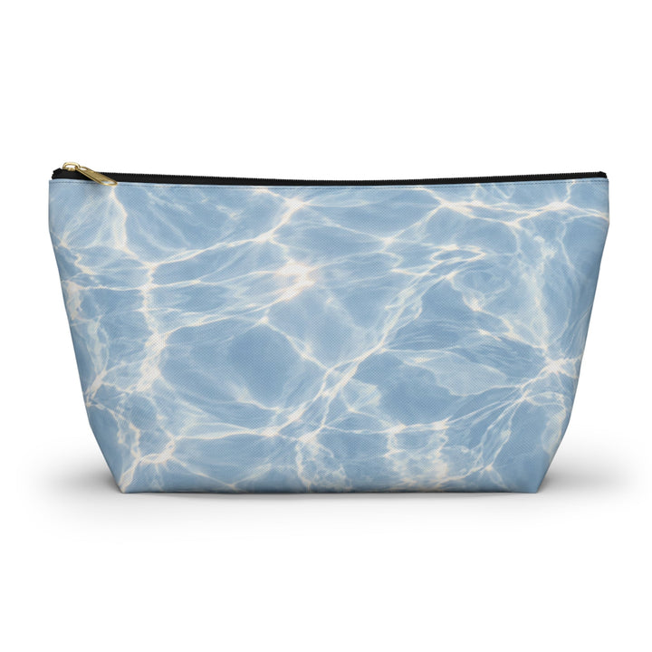 Sunday Theory blue T-bottom accessory pouch with a rippling water print and gold zipper, made of durable polyester.