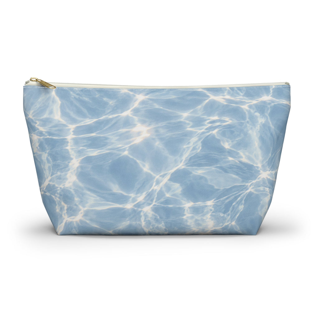 Sunday Theory blue T-bottom accessory pouch with a rippling water print and gold zipper for travel or cosmetics.