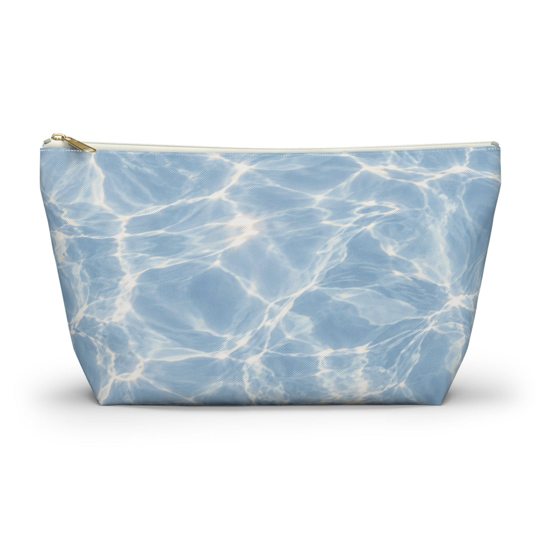 Sunday Theory blue T-bottom accessory pouch with a rippling water print and gold zipper for travel or cosmetics.