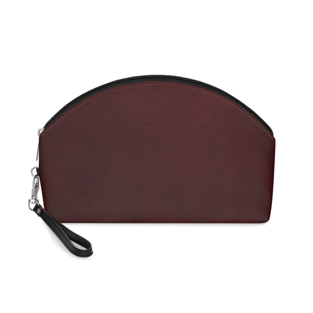 Sunday Theory burgundy leatherette cosmetic pouch with a black zipper and wrist strap on a white background
