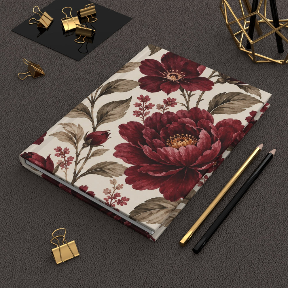 Sunday Theory vintage burgundy floral hardcover journal with matte finish, resting on a dark desk with gold stationery.