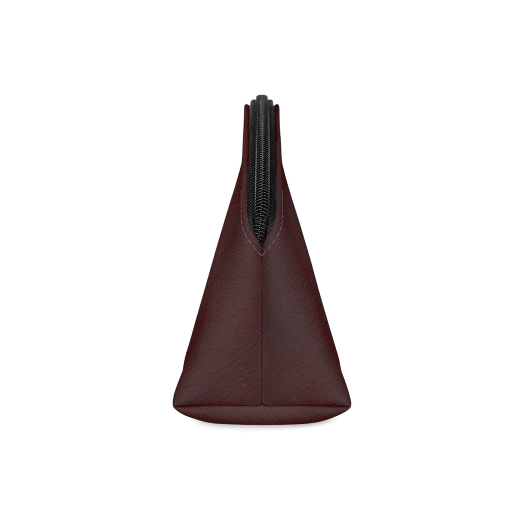 Sunday Theory burgundy faux leather makeup bag side view showing the curved shape and black zipper detail.