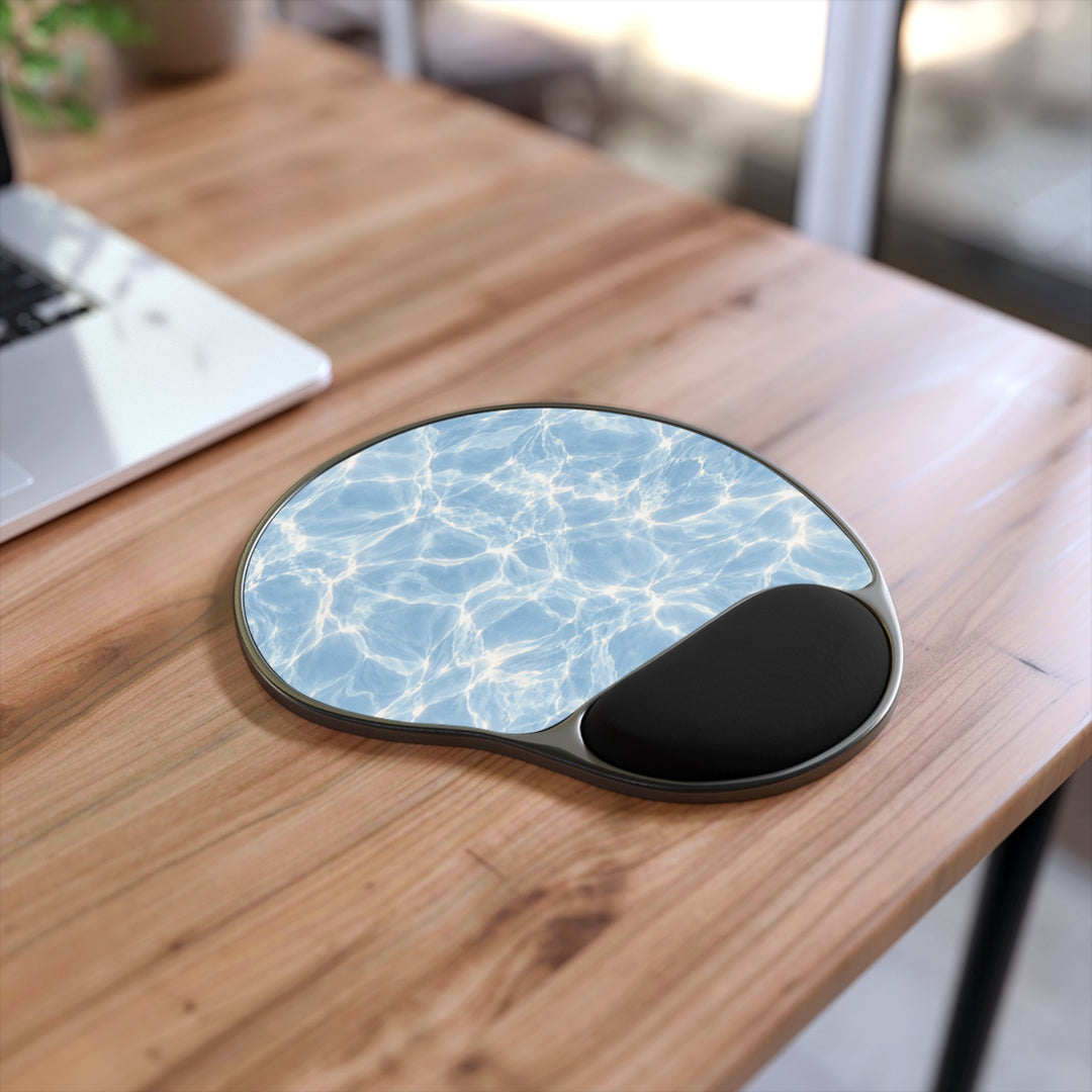 Sunday Theory ergonomic mouse pad with blue water ripple print and black memory foam wrist rest on a wooden desk.