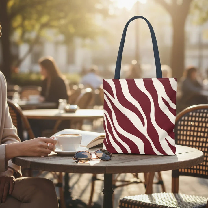 Sunday Theory maroon and cream zebra print tote bag sitting on an outdoor cafe table next to a coffee cup